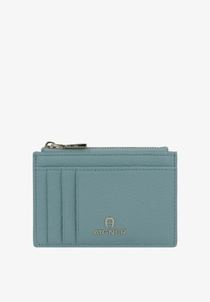 Un portacarte in pelle azzurra chiaro con quattro fessure per carte, una tasca con cerniera e un logo in tonalità oro in basso. Dettaglio della superficie testurizzata.