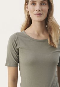Olivet grøn kortærmet t-shirt lavet af blødt stof, med rund halsudskæring og subtil tekstur. Simpelt design uden mønstre eller accenter.