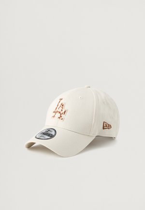 Beżowa czapka baseballowa z teksturowanym logo LA w kolorze miedzi. Posiada zakrzywiony daszek i haftowane akcenty. Wykonana z miękkiego materiału z regulowanym paskiem.