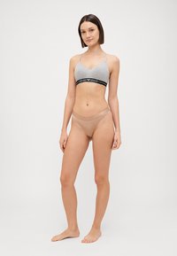 Gray cotton bralette with a black elastic band featuring "Emporio Armani" logo, paired with beige bikini-style panties with a slim waistband.