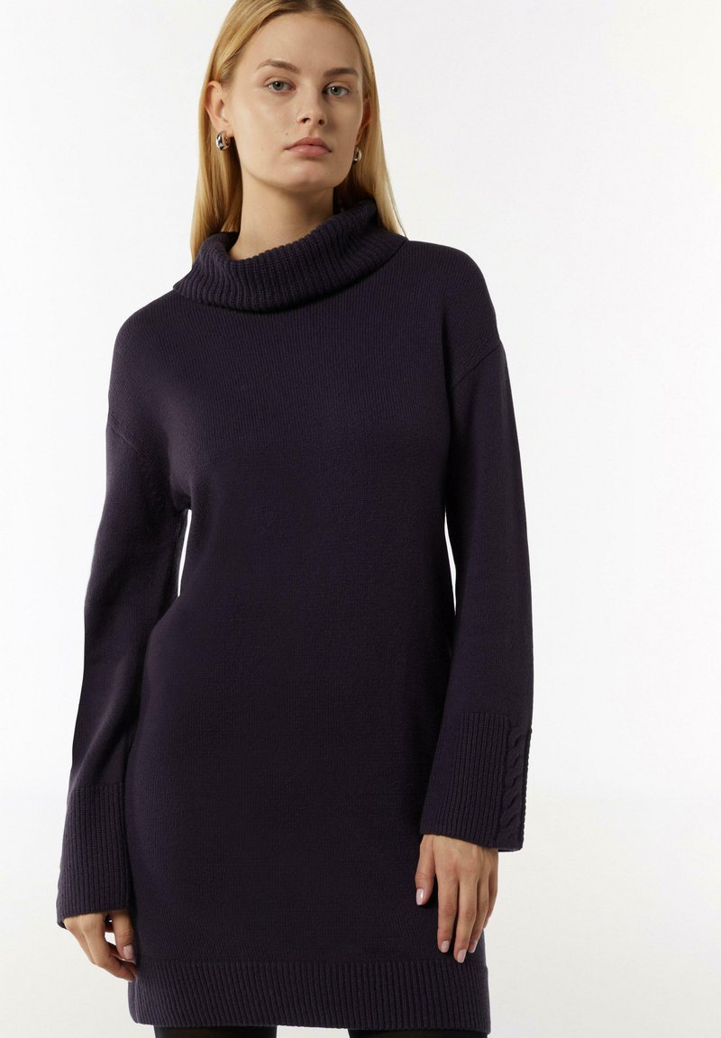 Dunkelviolettes Sweatkleid mit einem Schalkragen und gerippten Details an den Manschetten und dem Saum. Weicher Stoff, lockere Passform, Länge bis zur Mitte des Oberschenkels.