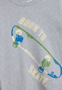 Felpa grigia con grafica di skateboard e dettagli blu, verdi e gialli. Testo che dice "BORN TO SKATE". Tessuto morbido, colletto rotondo.