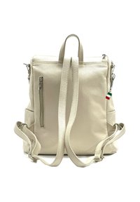 Beige leren rugzak met dubbele schouderbanden, een ritsvak aan de voorkant, zijvakjes en een Italiaans vlag charm detail. Textuur oppervlak.