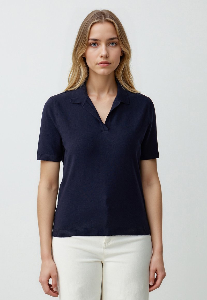 Granatowa, krótko rękawowa koszulka polo z dekoltem w kształcie V, prążkowanymi mankietami i gładką strukturą dzianiny, w zestawieniu z jasnymi spodniami typu straight-leg.