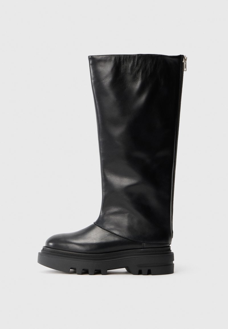 Bota de cuero negra hasta la rodilla con punta redondeada, suela de goma gruesa y cremallera lateral para cierre. Textura suave con un detalle mínimo.
