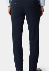 Marineblauwe katoen broek met een slim fit, voorzien van achterzakken, subtiele stikdetails en een gladde textuur, gecombineerd met zwarte schoenen.