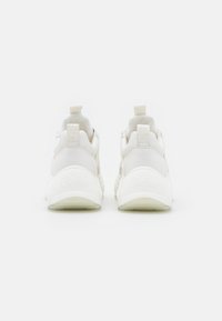 White sneakers with a smooth synthetic upper, rounded heel, and translucent sole. Features two pull tabs at the back and embossed branding.