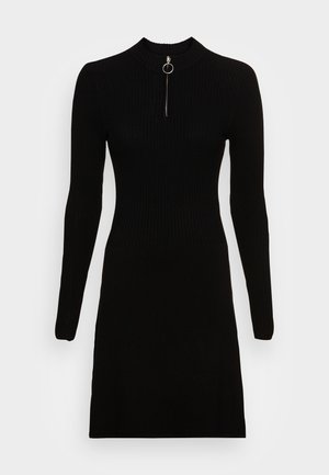 Robe noire en maille côtelée à manches longues avec un col montant et une courte fermeture éclair argentée à l'avant, dotée d'un tirette circulaire.