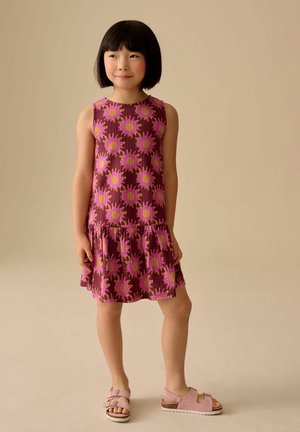 Blomsterkjole lavet af let materiale med lilla baggrund og pink solstrålemønster, lagdelt nederdel, rund halsudskæring og ærmeløs design.