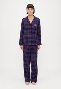 Μωβ καρό πιτζάμα από μαλακό ύφασμα, που περιλαμβάνει πουκάμισο με κουμπιά και γιακά καθώς και αντίστοιχους χαλαρούς παντελόνες. Διακοσμητική κεντητική λεπτομέρεια στο πουκάμισο.