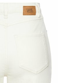 Weiße Denim-Jeans mit einem Lederpatch mit "camel active" Branding, Gesäßtaschen und einer glatten, strukturierten Oberfläche.