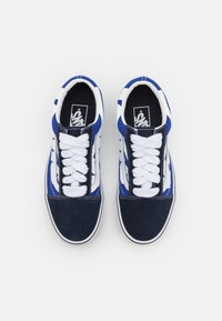 Sinine ja valge sneaker, mis on valmistatud segust nahast ja kangast, lame valge paeltega, ümar varvas ja külgmine triibudisain.