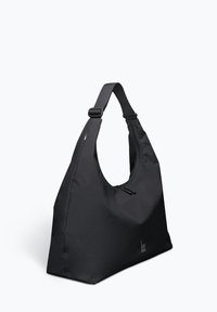 Schwarze Nylon-Schultertasche mit großer, geschwungener Form, verstellbarem Tragegurt und Reißverschluss oben. Mit einem Logo, das am Boden aufgedruckt ist.