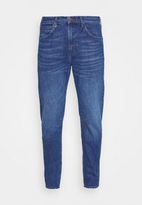 Jeans de mezclilla azul oscuro con corte entallado, que cuentan con cinco bolsillos, cierre de botón y un ligero desgaste en los muslos. Textura suave.