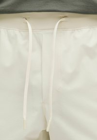 Lysfarvede joggers med en tekstureret finish, der har en elastisk talje og hvide snore med plasttips.