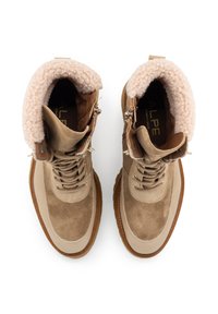 Stivaletti alla caviglia in suede beige con un colletto in morbida e calda pelliccia di colore marrone chiaro, lacci tondi e suola in gomma. Sono visibili occhielli dorati e dettagli con cerniera.