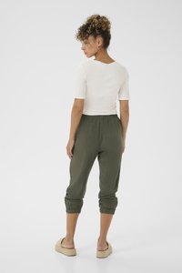 Hvid ribbet kortærmet top parret med olivengrønne tapered bukser med elastiske manchetter. Modellen har beige espadriller på.