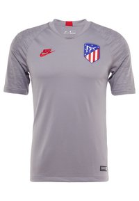 Šedý sportovní dres Nike s krátkým rukávem, žebrovaným límcem, logem v červené barvě a emblémem ve tvaru štítu s červenými, bílými a modrými akcenty.