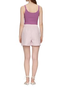 Lila gestreifter Tanktop kombiniert mit hellrosa gestreiften Shorts. Die Shorts verfügen über einen elastischen Bund und Seitentaschen.