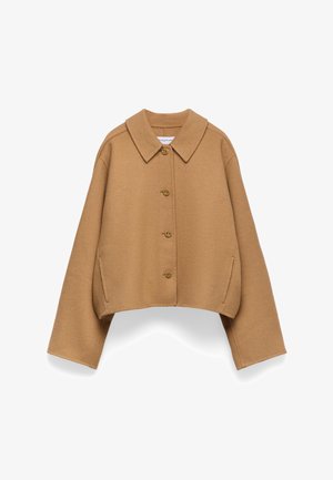 Giacca croppata marrone con grande colletto, cinque bottoni e tasche laterali. Realizzata in tessuto morbido e testurizzato. Vestibilità ampia e design minimal.