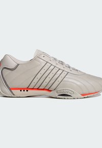 Grauer Ledersportschuh mit drei dunkelgrauen Streifen, orangefarbenen Akzenten an der Sohle und einer glatten Textur. Verfügt über eine runde Zehenpartie und ein Schnürdesign.