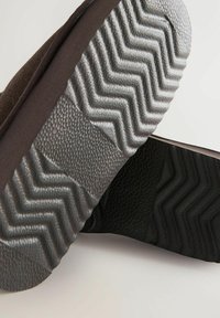 Tumepruun king, millel on tekstuuriga must kummist tald, mis on kaunistatud siksakmustriga, ja siledast, liigilisest ülematerjalist.