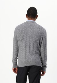 Suéter gris de punto que presenta un patrón de trenzas, con puños y dobladillo acanalados. La parte posterior muestra un diseño limpio y sin costuras, sin adornos.