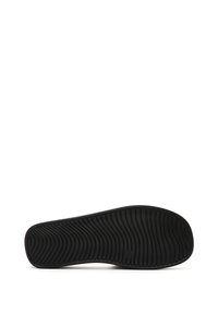 Suola di scarpa nera con motivo testurizzato, caratterizzata da scanalature e rilievi curvi per una migliore trazione. Il materiale è gomma, progettato per la durata.