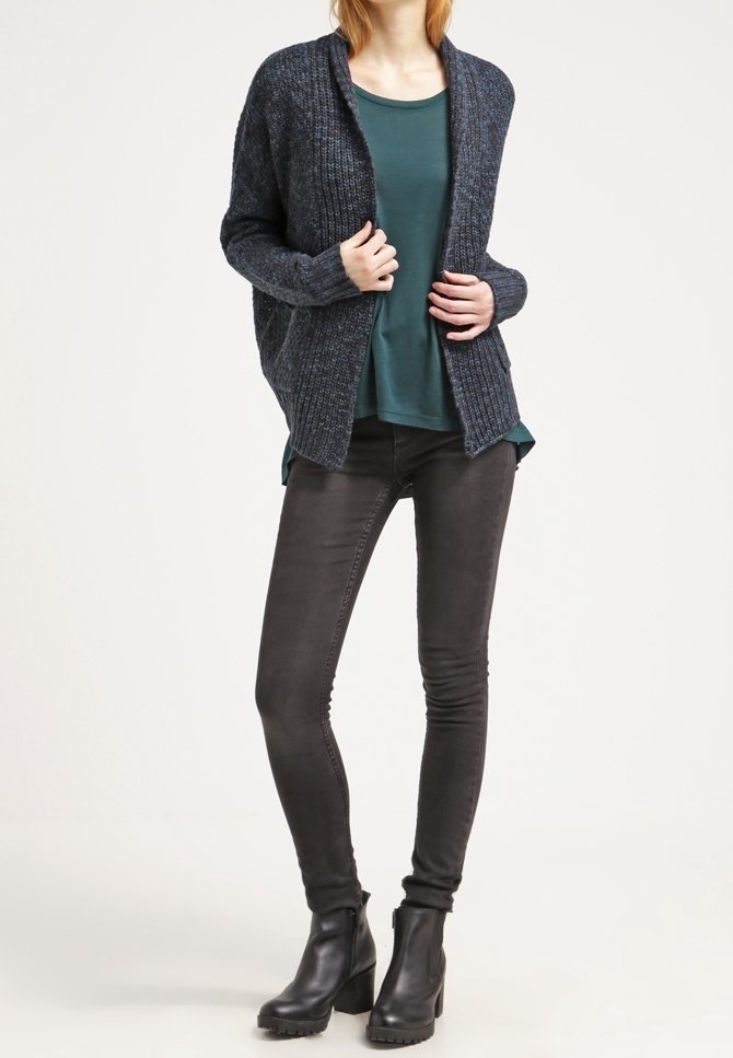 Merinovillan raidallinen neuletakki tummansinisellä pohjalla, päällä teal-värinen toppi, ja yhdistetty mustiin skinny-farkkuihin sekä mustiin nilkkakenkiin. Asu on rento ja casual-tyylinen.