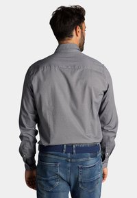Herenoverhemd met een micro-patroon in marineblauw en lichtblauw, met een button-down kraag en lange mouwen, gecombineerd met blauwe spijkerbroeken en een geweven riem.