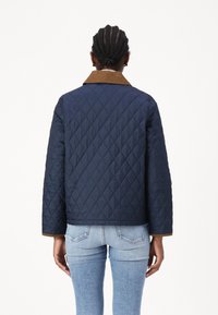 Granatowa pikowana kurtka z brązowym kołnierzem z kordurowej tkaniny, długimi rękawami i skróconym krojem, z geometrycznymi detalami wyszycia.