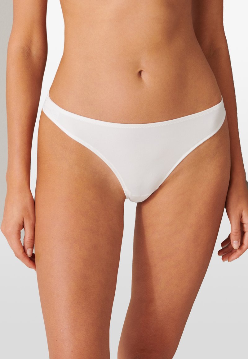 Bas de bikini blanc en tissu lisse, avec une coupe taille basse et des bandes latérales minimales. Design simple sans motifs ou accents visibles.