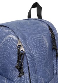 Zaino blu a fantasia realizzato in tessuto resistente, con cerniere nere, superficie texturizzata e cordini annodati per una chiusura sicura.