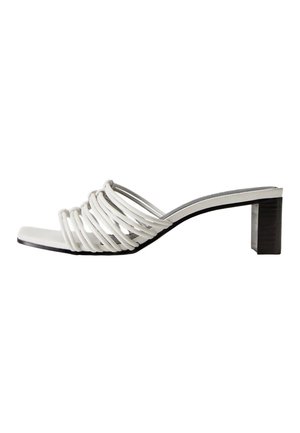 Mule blanche à brides avec un petit talon bloc et un bout carré, présentant plusieurs fines brides sur le devant.