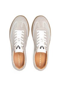 Zapatillas de ante gris con cordones blancos, que cuentan con un diseño curvo, acentos blancos en contraste y una suela de goma marrón. Logo de la marca visible en el interior.
