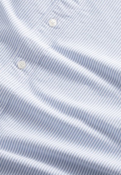 Blauw-wit gestreepte stof met een gladde textuur. Twee witte knopen zijn zichtbaar, wat een detail toevoegt aan het shirtontwerp.