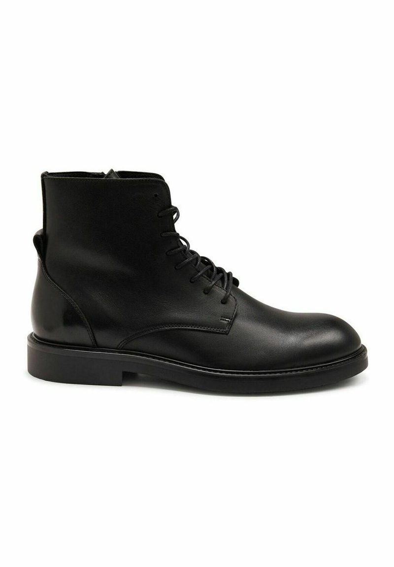 Bottines en cuir noir avec une texture lisse, bout rond et design à lacets. Présentent un talon bas et robuste ainsi que des détails de couture minimaux.