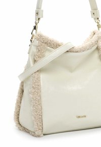 Sac à main en cuir blanc avec un élégant bord en shearling beige, présentant une forme structurée, une bandoulière ajustable et des accents en métal doré.