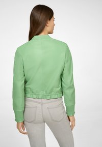 Grüne Lederbomberjacke mit geripptem, gerafftem Saum und Bündchen. Die Rückansicht zeigt eine glatte Textur und ein einfaches Kragen Design.