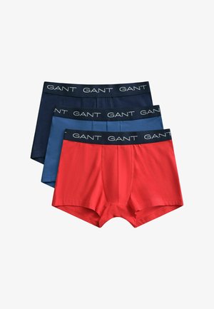 Trois caleçons boxers pour hommes en rouge, bleu moyen et bleu marine, chacun avec une ceinture noire portant le nom de la marque GANT en blanc.