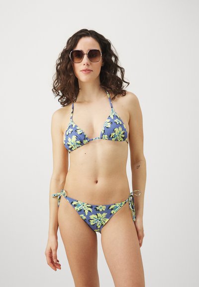 Bikini rinkinys, kuriame yra mėlyna bazė su geltonu gėlių raštu, laisvai kabinamas viršus ir užrišamos bikinio kelnaitės šonai. Lygus audinys su minimalia danga.