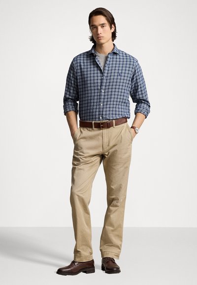 Blå och grå rutigt button-up skjorta, beige byxor, brun läderbälte och bruna skor. Avslappnad outfit med en klassisk design.