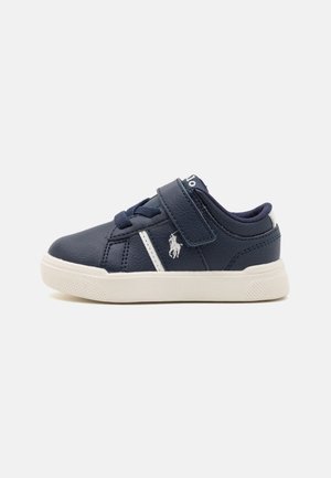 Navyblaue Ledersneaker mit weißen Akzenten und einem Klettverschluss. Zu den Merkmalen gehören eine strukturierte Sohle und ein kleines Logo an der Seite.