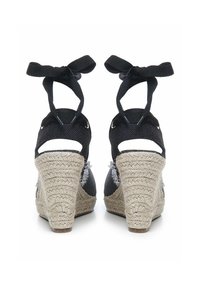 Zwarte espadrilles met sleehak van geweven jute, met een gestreepte achterkant en stoffen banden om de enkel. Soepele materialen en degelijke constructie.