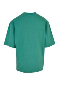 Tricou oversized teal, fabricat din bumbac moale. Are mâneci scurte, un guler rotund și o textură netedă, fără modele sau accente vizibile.