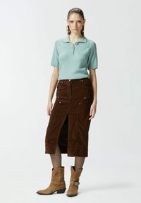 Svijetloplava pletena polo majica s kratkim rukavima, u kombinaciji s smeškom od kordura s prednjim prorezom i srebrnim detaljima. Bež čizmice do gležnja.