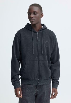 Mørkegrå hættejakke med lynlås fremstillet af blødt stof. Har en frontlomme, justerbare snore og en logopatch på venstre bryst.