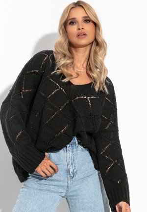 Czarny sweter z dzianiny o wzorze rombów i luźnym kroju, zestawiony z jasnoniebieskimi dżinsami o wysokim stanie.