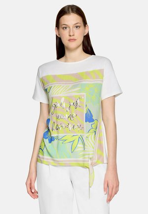 Kvinde iført hvid kortærmet skjorte med pastelblomstret og zebrastribet tryk, tekst "girls just wanna have sun" og sidestikdetalje.