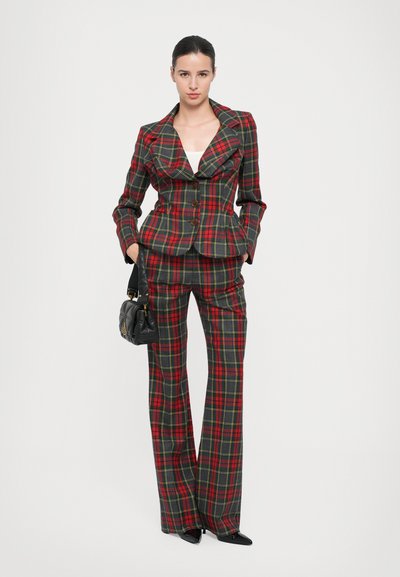 Red and green plaid suit with a fitted jacket and wide-leg pants, featuring a notched collar and three brown buttons. Black handbag included.